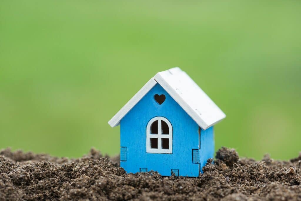 Wooden house model on plot of land close up. Real estate business. Cottage for sale. Selling